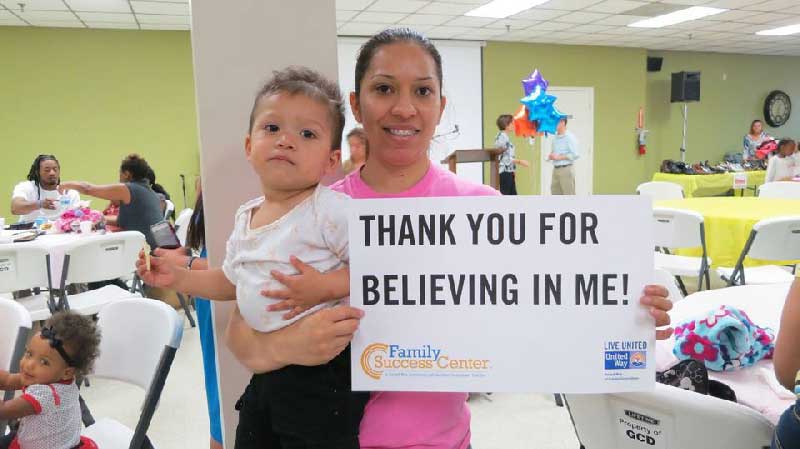 Family holding sign that says 'thank you for believing in me'