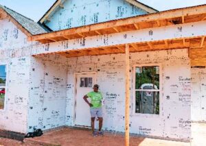 Habitat for Humanity homeowner posing on porch of under construction home